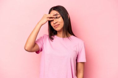 Pembe arka planda izole edilmiş genç İspanyol kadın başı ağrıyor, yüzüne dokunuyor..