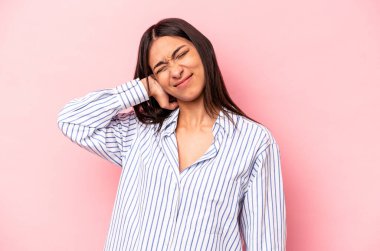 Pembe arka planda izole edilmiş genç İspanyol kadın stresten dolayı boynu ağrıyor, masaj yapıyor ve elle dokunuyor..