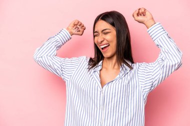 Pembe arka planda izole edilmiş genç İspanyol kadın zaferden sonra yumruğunu kaldırıyor, kazanan konsept..