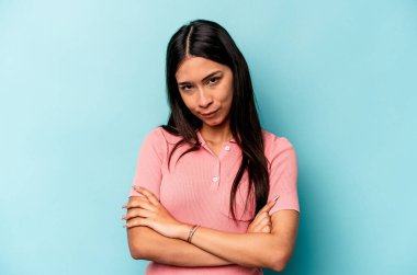 Mavi arka planda izole edilmiş genç İspanyol kadın. Sıkılmış, yorgun ve dinlenmeye ihtiyacı var..