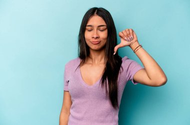 Mavi arka planda izole edilmiş genç İspanyol kadın hoşlanmadığı bir hareket gösteriyor. Anlaşmazlık konsepti.