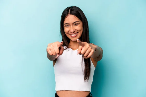 Young hispanic woman isolated on blue background cheerful smiles pointing to front.