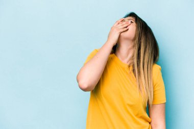 Mavi arka planda soyutlanmış genç beyaz kadın gülüyor, kaygısız, doğal duygu..