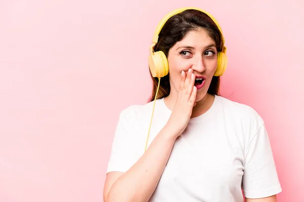 Young Caucasian Woman Listening Music Isolated Pink Background Saying Secret — Φωτογραφία Αρχείου