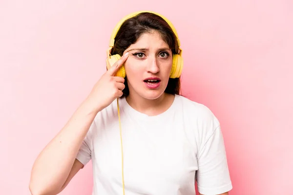 Young Caucasian Woman Listening Music Isolated Pink Background Showing Disappointment — Φωτογραφία Αρχείου