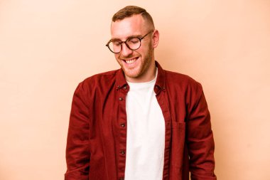 Beyazların arka planında izole edilmiş genç beyaz adam gülüyor ve gözlerini kapatıyor, rahatlamış ve mutlu hissediyor..