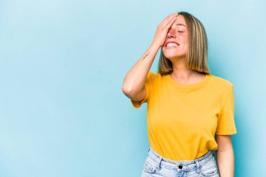 Mavi arka planda soyutlanmış genç beyaz kadın gülüyor, kaygısız, doğal duygu..