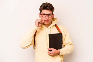 Beyaz arka planda izole edilmiş beyaz tenli genç bir öğrenci. Parmakları dudaklarında bir sır saklıyor..