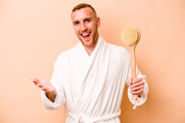 Beyaz tenli genç adam bej arka planda izole edilmiş, heyecanlı ve heyecanlı bir şekilde el kaldırıyor..