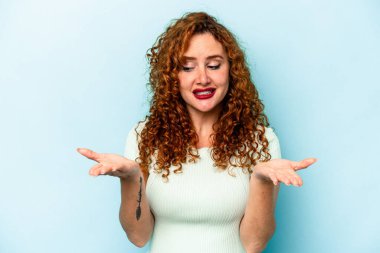 Genç, beyaz, mavi arka planda izole edilmiş bir kadın elinde avuç içi bir şeyle kameraya sunuyor..