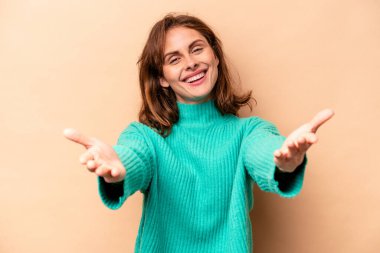 Beyazlı genç bir kadın bej arka planda izole edilmiş kameraya sarılıyor..