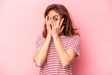 Pembe arka planda izole edilmiş genç beyaz kadın parmaklarıyla gözünü kırp korkmuş ve gergin..