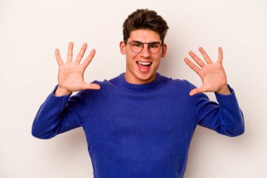 Beyaz arka planda izole edilmiş beyaz tenli genç adam on numarayı elleriyle gösteriyor..