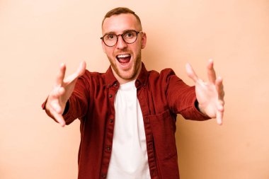 Beyazlı genç bir adam bej arka planda izole edilmiş bir şekilde zaferi veya başarıyı kutluyor. Şaşırmış ve şok olmuş..