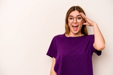 Beyaz arka planda izole genç beyaz kadın yüksek sesle bağırıyor, gözleri açık ve elleri gergin tutuyor..