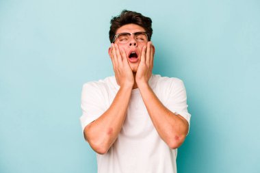Kafkasyalı genç adam mavi arka planda izole edilmiş sızlanıyor ve ağlıyordu..