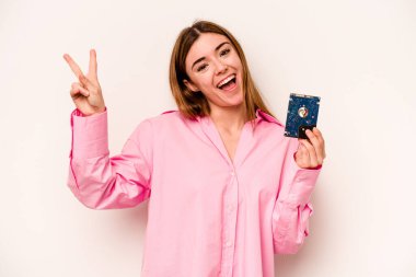 Beyaz arka planda izole edilmiş genç, gayri resmi beyaz kadın neşeli ve kaygısız parmaklarıyla barış sembolü gösteriyor..