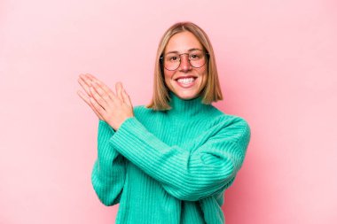 Pembe arka planda soyutlanmış genç beyaz kadın enerjik ve rahat hissediyor, ellerini ovuşturuyor..