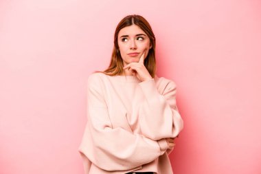 Pembe arka planda izole edilmiş genç beyaz kadın bir strateji planlıyor, bir iş kurmanın yollarını düşünüyor..