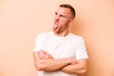 Beyazlı genç bir adam bej arka planda izole edilmiş komik ve dost canlısı bir dil kullanıyor..