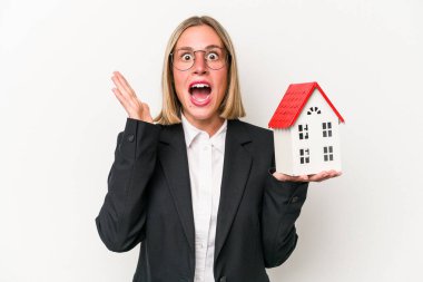 Beyaz arka planda izole edilmiş oyuncak evi tutan beyaz kadın şaşırdı ve şok oldu..