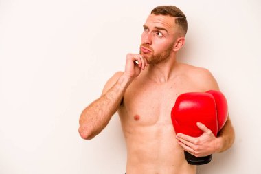 Beyaz arka planda boks yapan beyaz tenli genç adam şüpheli ve şüpheci bir ifadeyle yana bakıyor..