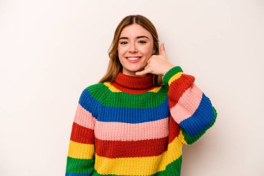 Beyaz arka planda izole edilmiş genç beyaz kadın parmaklarıyla bir cep telefonu hareketi gösteriyor..