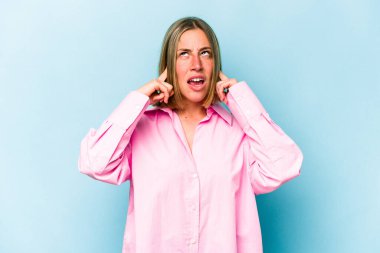 Genç beyaz kadın mavi arka planda izole edilmiş parmaklarıyla kulaklarını kapatıyor, gürültülü bir ortam yüzünden stresli ve çaresiz..