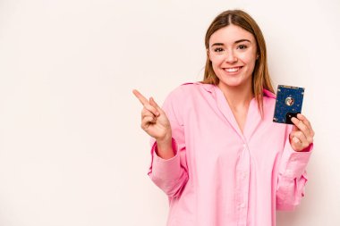 Beyaz arka planda izole edilmiş genç, gayri resmi beyaz kadın gülümsüyor ve boş alanda bir şeyler gösteriyor..