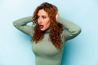Mavi arka planda izole edilmiş genç, beyaz bir kadın çığlık atıyor, çok heyecanlı, tutkulu, bir şeyden memnun..