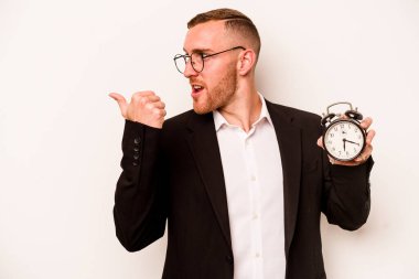 Kafkasyalı genç bir adam çalar saati beyaz arka plan noktalarından soyutlamış, başparmak uzakta, gülüyor ve kaygısız..