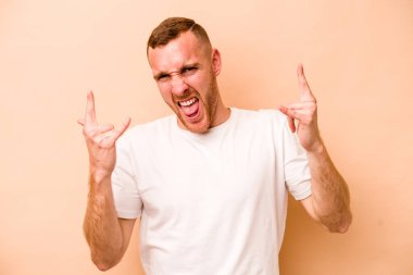 Beyazlı genç bir adam bej arka planda izole edilmiş boynuzlarını devrim konsepti olarak gösteriyor..