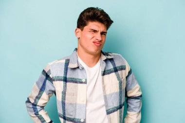 Kafkasyalı genç adam mavi arka planda izole edilmiş üzgün, ciddi yüzlü, mutsuz ve hoşnutsuz..