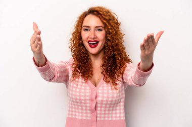 Beyaz arka planda izole edilmiş genç, beyaz tenli bir kadın zaferi veya başarıyı kutluyor, şaşırıyor ve şok oluyor..