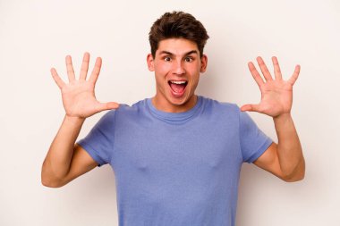 Beyaz arka planda izole genç beyaz adam hoş bir sürpriz alıyor, heyecanlı ve el kaldırıyor..