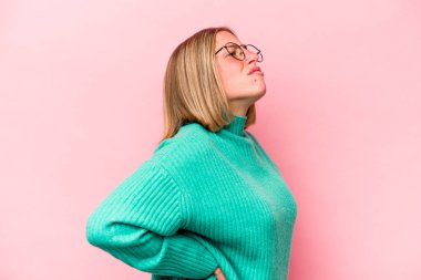 Pembe arka planda izole edilmiş beyaz bir kadın sırt ağrısı çekiyor..