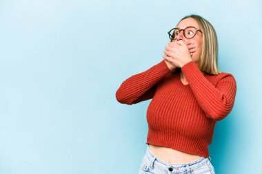 Kafkasyalı genç bir kadın mavi arka planda izole edilmiş düşünceli bir şekilde ağzıyla ağzını kapatan bir fotokopi odasına bakıyor..