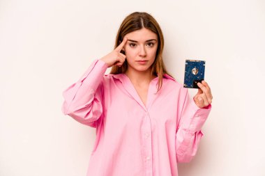 Beyaz arka planda izole edilmiş genç, gayri resmi beyaz kadın şakağı parmağıyla işaret ediyor, düşünüyor ve bir göreve odaklanıyor..