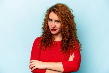 Genç, beyaz, mavi arka planda izole edilmiş, iğneleyici bir ifadeyle kameraya bakan mutsuz bir kadın..