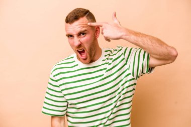Beyazların arka planında izole edilmiş genç beyaz bir adam işaret parmağıyla hayal kırıklığı jesti yapıyor..