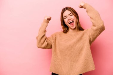 Pembe arka planda izole edilmiş beyaz bir kadın zaferden sonra yumruğunu kaldırıyor, kazanan konsept.