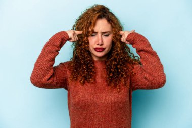 Mavi arka planda izole edilmiş genç beyaz kadın bir işe odaklanmış, işaret parmaklarını işaret ediyor..