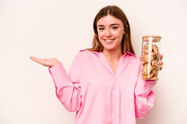 Beyaz arka planda izole edilmiş kurabiye kavanozu tutan genç beyaz kadın bir avuç içinde fotokopi alanı ve belinde başka bir el tutuyor..