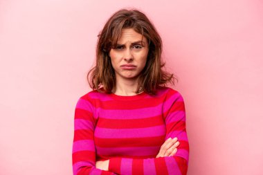 Pembe arka planda izole edilmiş genç beyaz kadın alaycı bir ifadeyle kameraya bakıyor..
