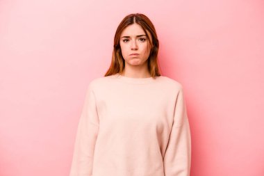 Pembe arka planda izole edilmiş genç beyaz kadın yanakları patlatıyor, yorgun bir ifade takınıyor. Yüz ifadesi kavramı.