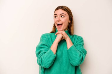 Beyaz arka planda izole edilmiş genç beyaz bir kadın şans için dua ediyor, şaşırmış ve ağzını açıp önüne bakıyor..