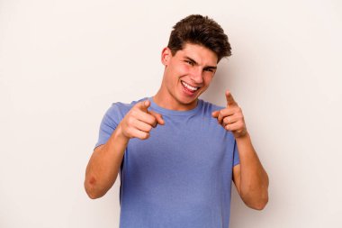 Beyaz arka planda izole edilmiş genç beyaz adam parmaklarıyla ön tarafı işaret ediyor..