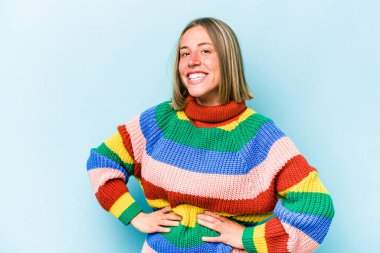 Mavi arka planda izole edilmiş genç beyaz kadın mutlu, güler yüzlü ve neşeli..