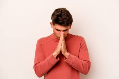 Beyaz arka planda izole edilmiş genç beyaz adam dua ediyor, bağlılık gösteriyor, dindar biri ilahi ilham arıyor..