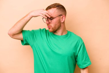 Kafkasyalı genç bir adam bej arka planda izole edilmiş, başı ağrıyor, yüzüne dokunuyor..